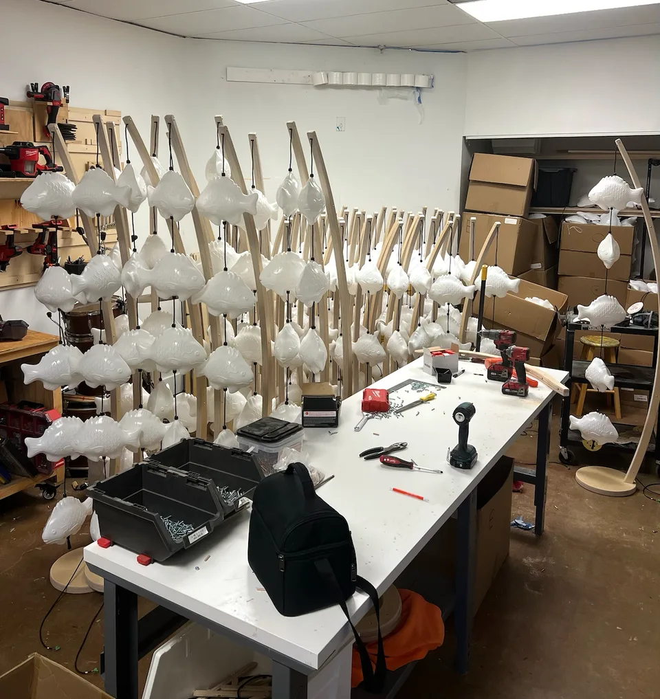The first assembled floor fish lamps lined up around a workbench in the workshop