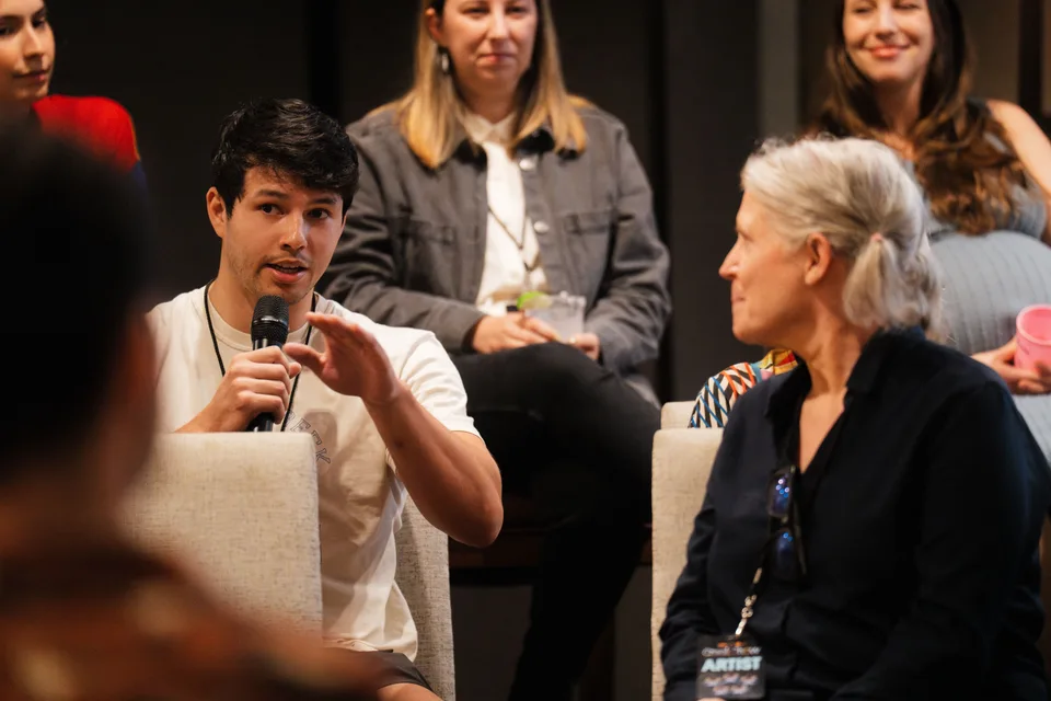 Broose speaking into a microphone at a Creek Show artist talk